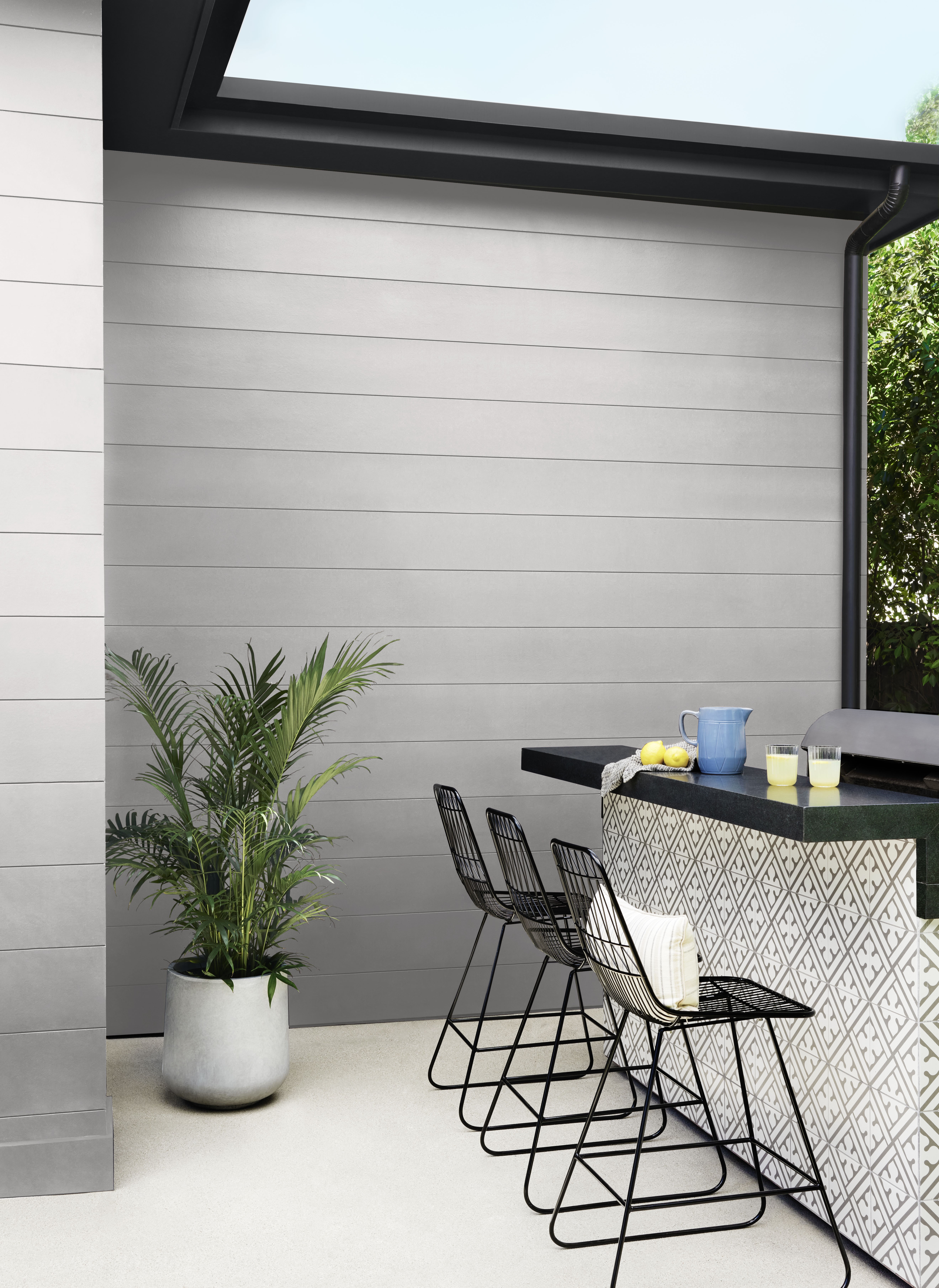 An outdoor bar featuring a bold black and white patterned front, set in front of a light purple-grey house, creating a stylish and modern entertaining space.