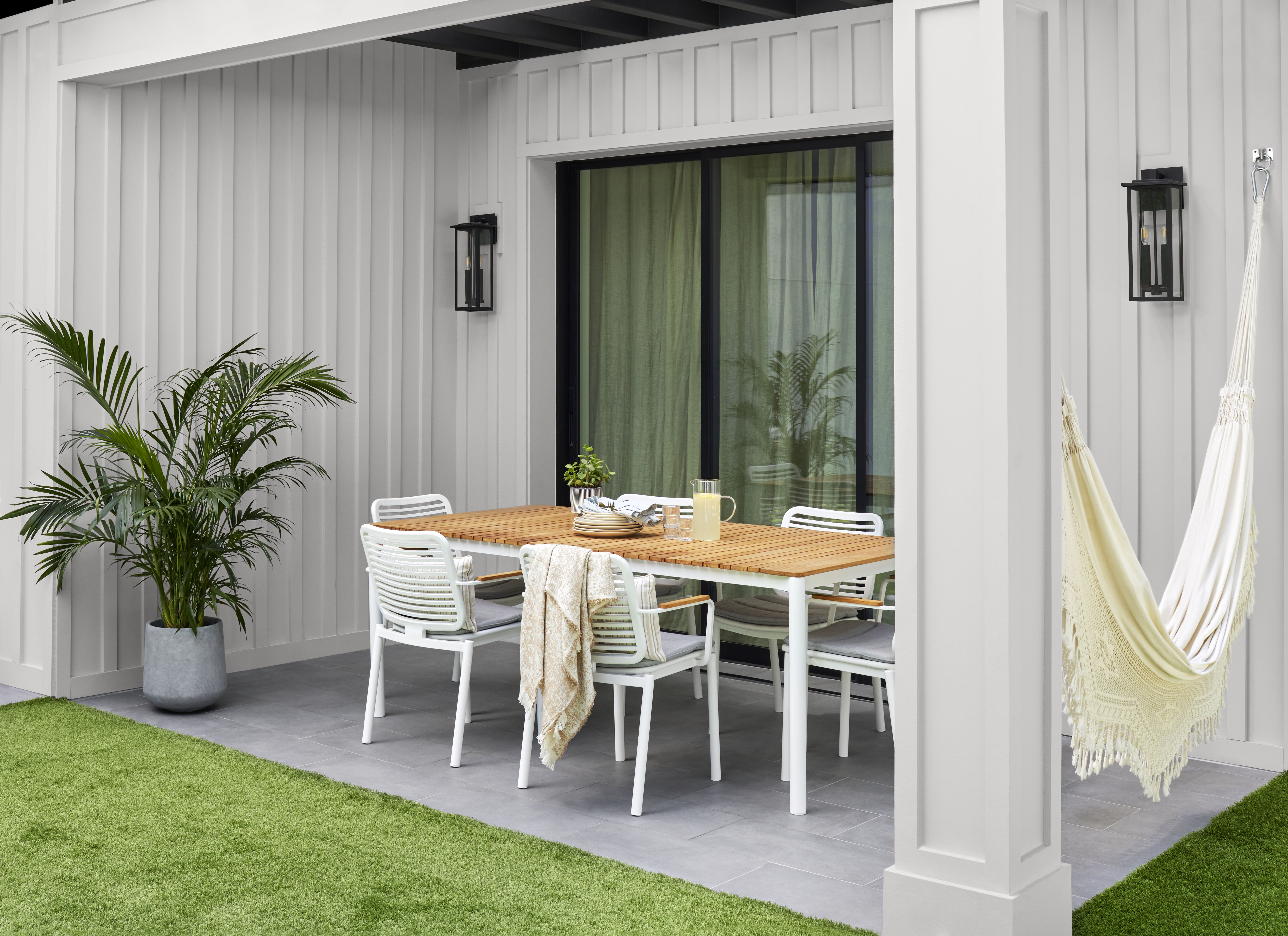 Outdoor patio of a house with a welcoming dining area, featuring a large table, comfortable seating, and warm, inviting décor ideal for gatherings.