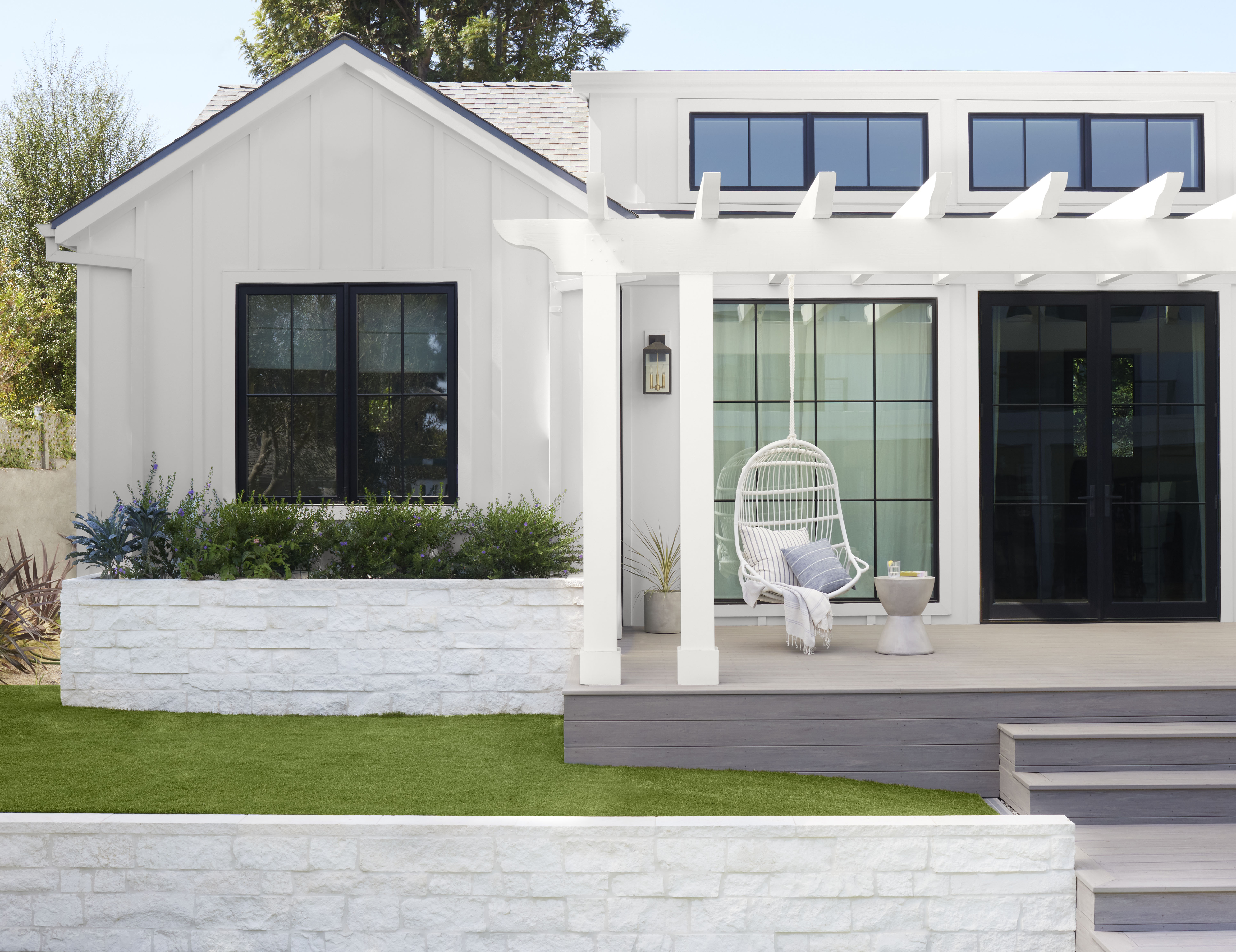 A light-coloured house with a front porch featuring a hanging swing, creating a cozy and inviting outdoor space.