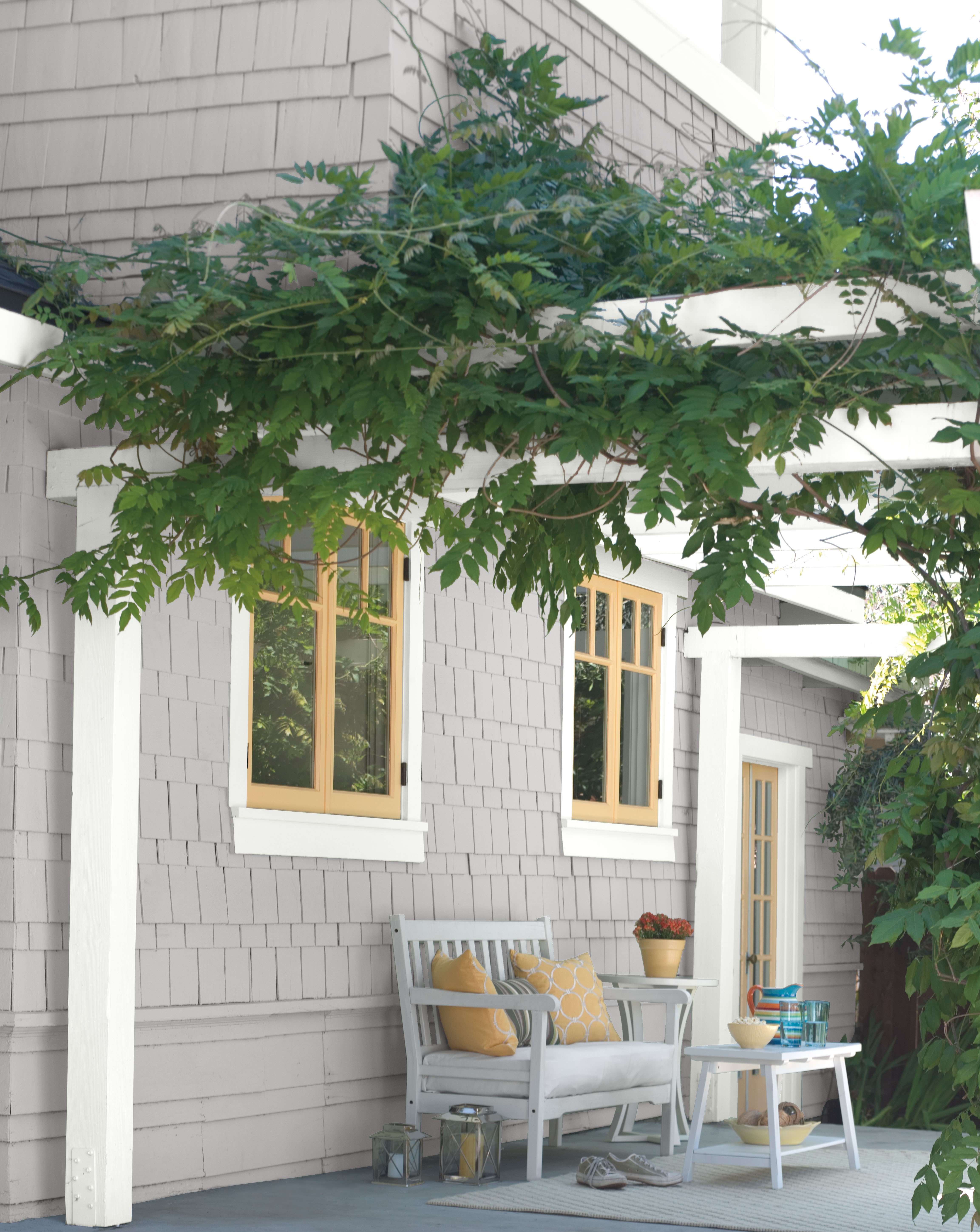 Charming cottage with grey painted exterior, white trim, and cheerful yellow accents on the door and window frames, creating a bright and inviting appearance.
