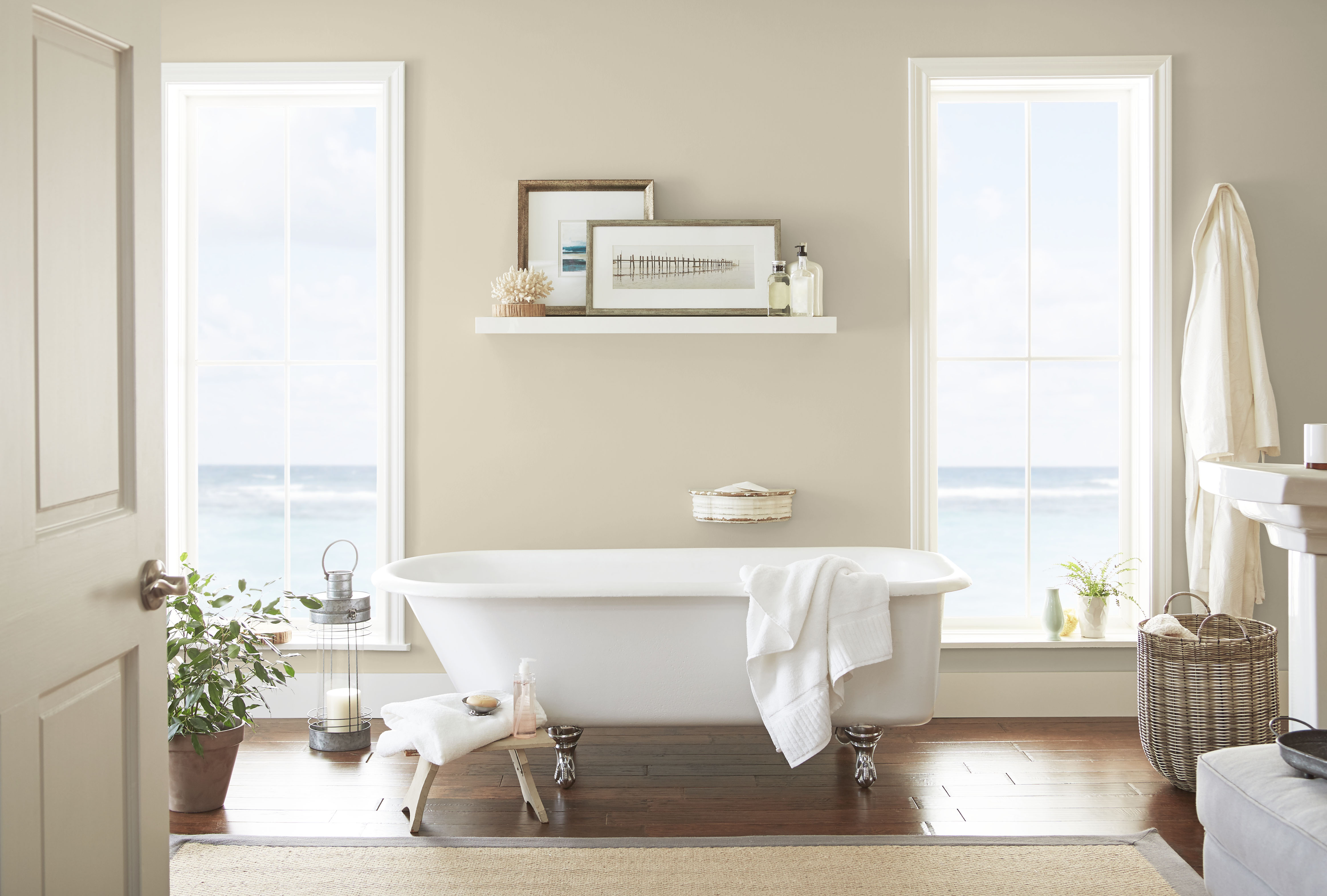 A bathroom with large windows overlooking the ocean and walls painted in a soft beige hue.