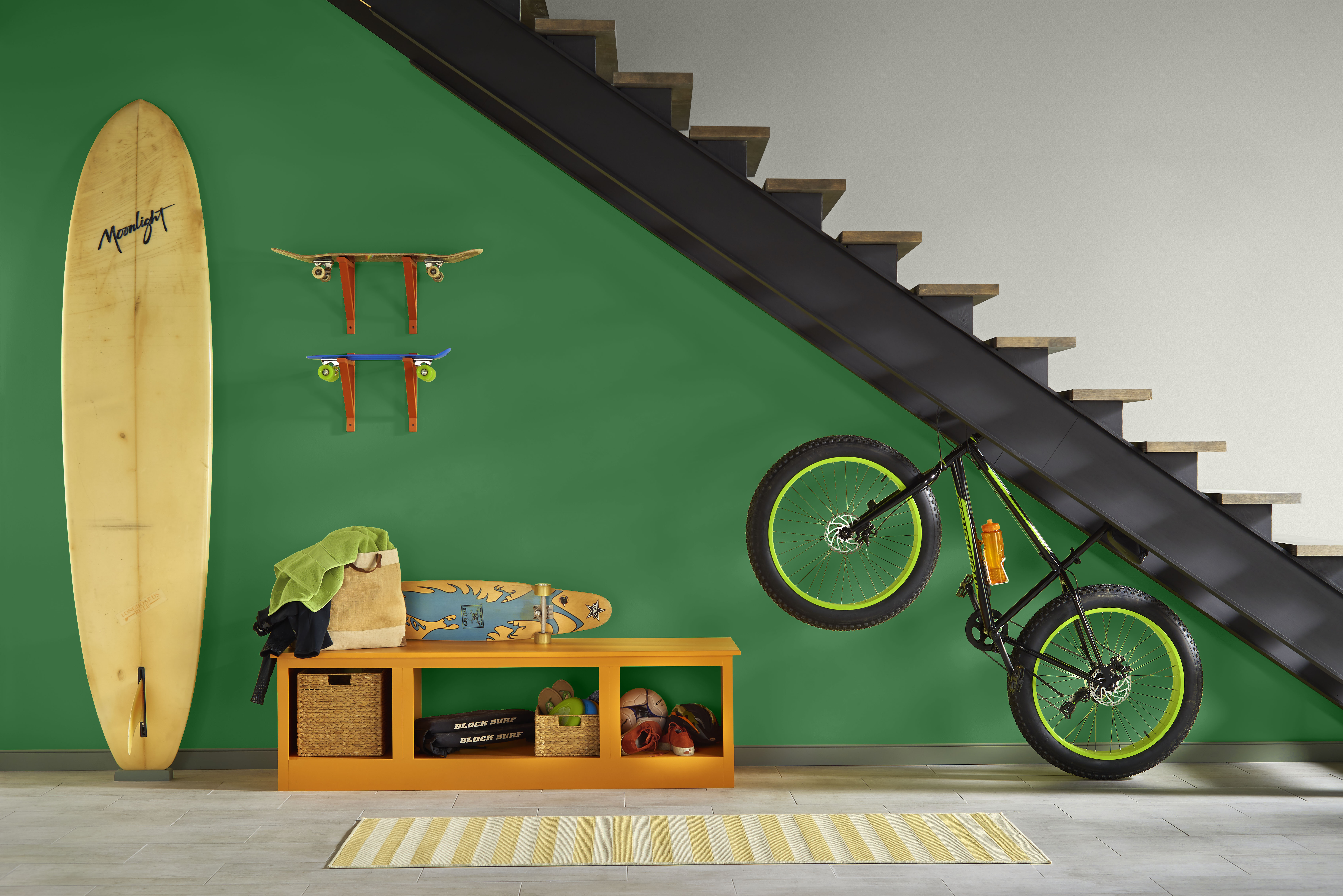 A storage area for bikes and surfboards with the wall in a dark emerald, green hue.