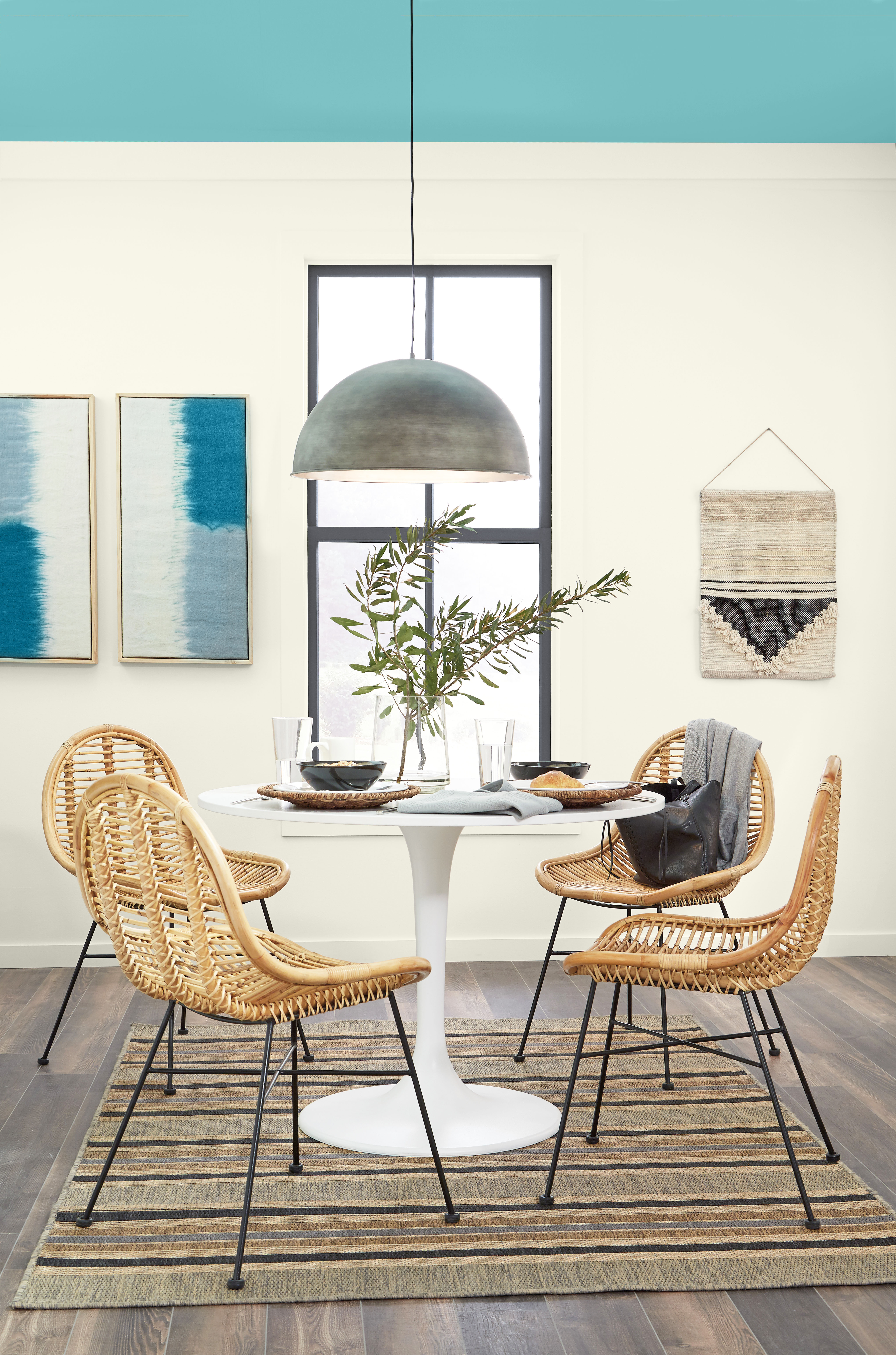 A dining nook with walls in a pearly white hue and ceiling in a vibrant blue-green tone.