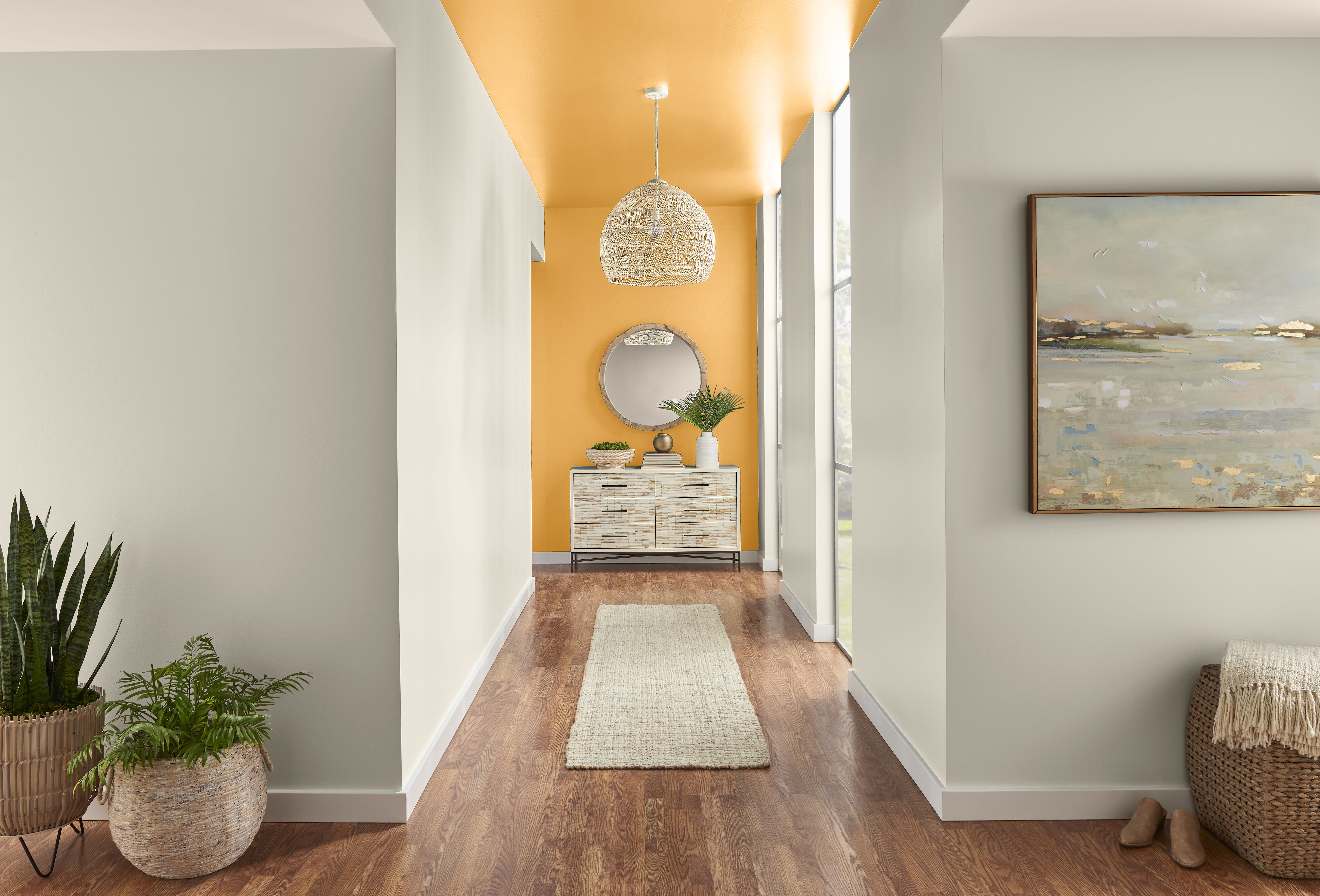 A stylish hallway featuring chic furniture and decor, warm hardwood flooring, and a striking accent wall painted in Jackfruit yellow, adding a vibrant and modern touch to the sophisticated space.