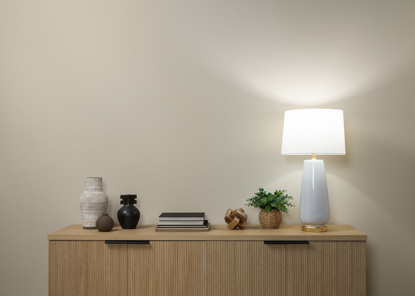 Image shows a minimalist, modern stand up against a beige wall. There is a lamp set up with daylight lighting.