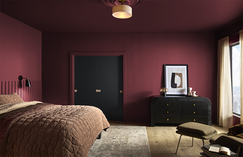 The image depicts a stylish bedroom with a dramatic and cozy aesthetic with the walls, ceiling and trim being painted in the same bold colour.