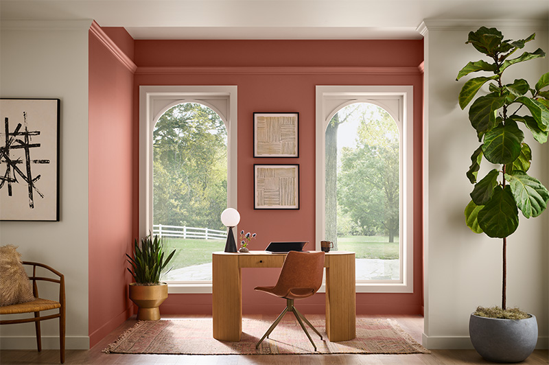 A home office nook with two windows that allow natural light to flood in, softening the terra cotta colour and bringing warmth and balance to the overall atmosphere. 