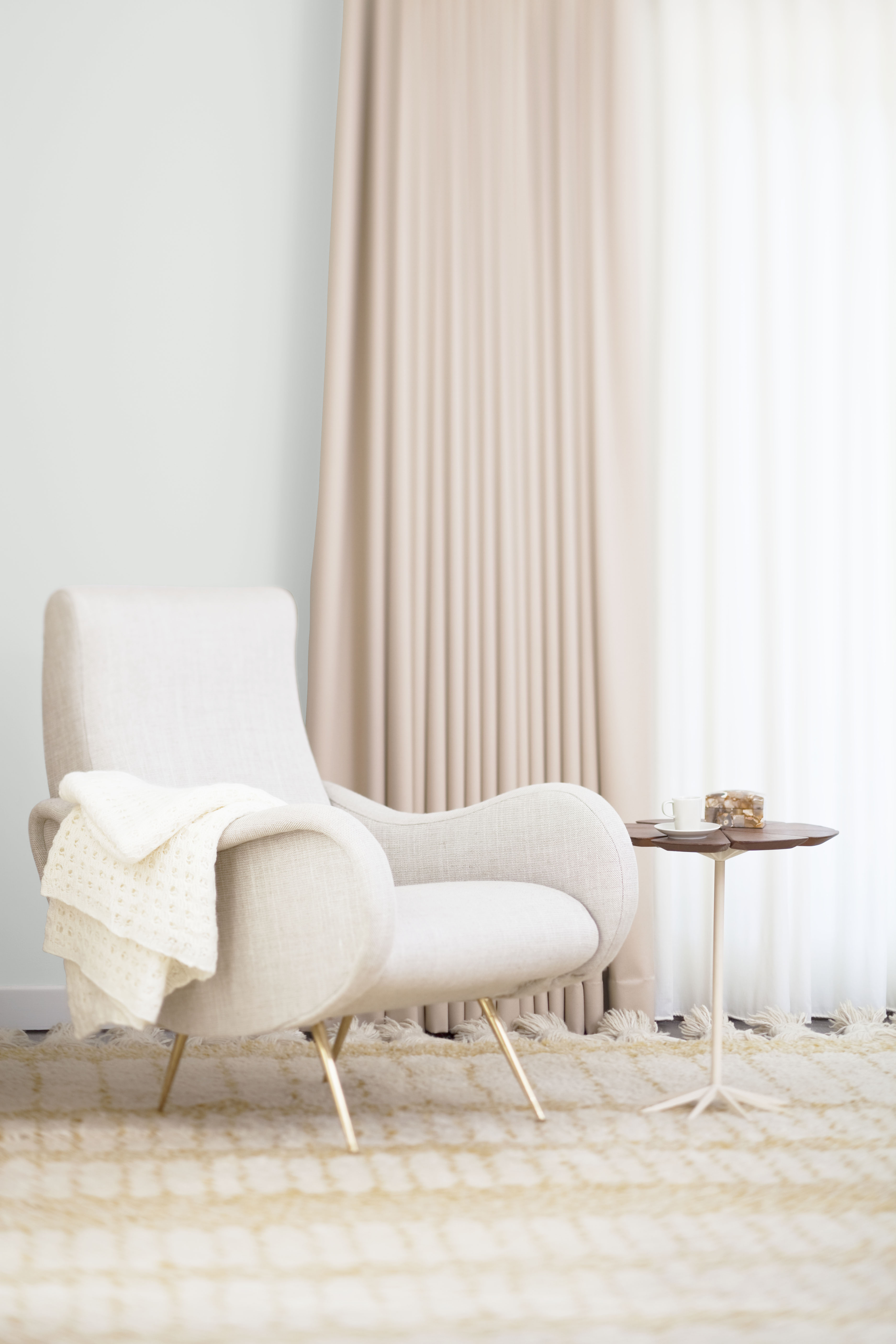 A cozy corner with the wall painted in a warm muted white.)