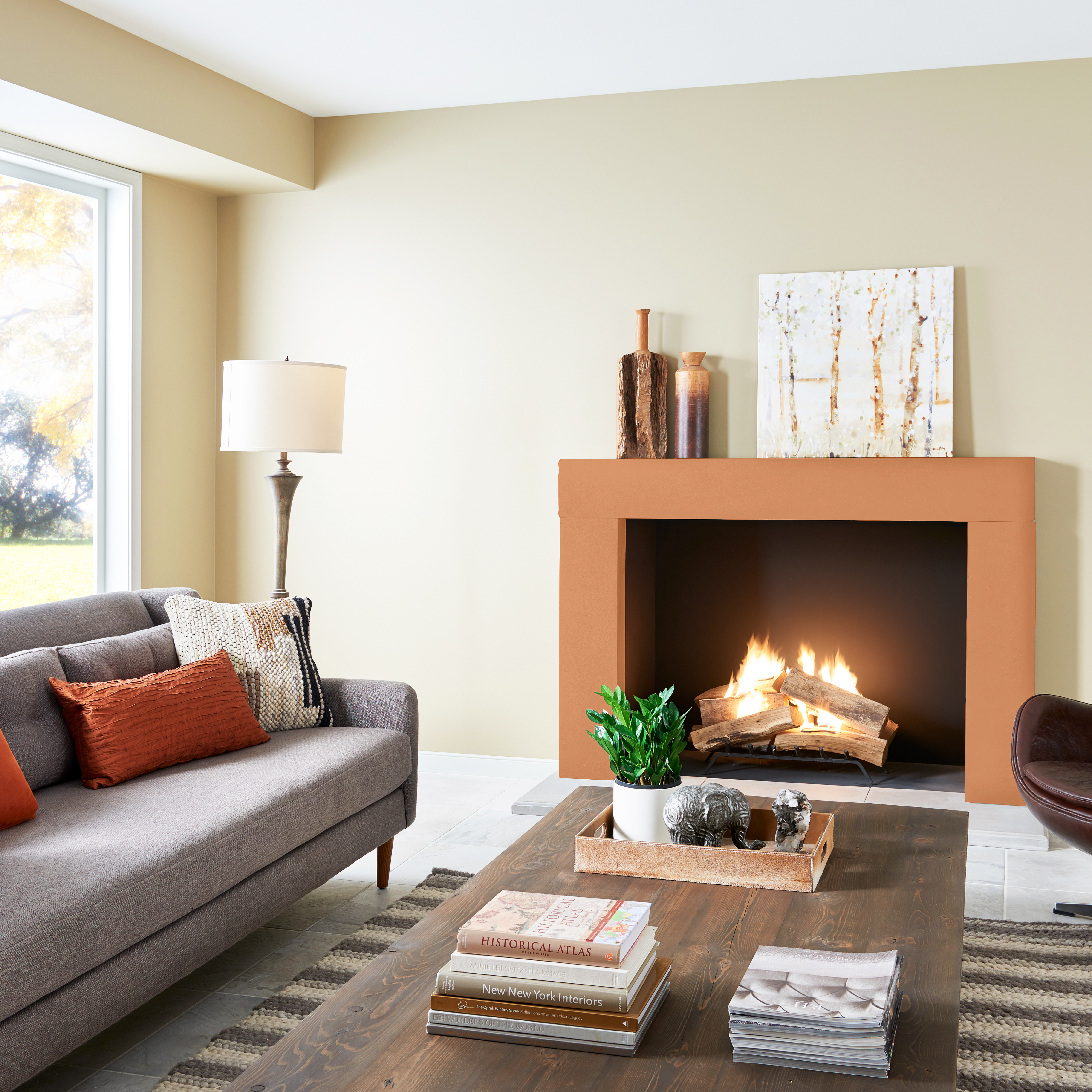 A living room with creamy white walls and a fireplace painted in a bright orange colour.
