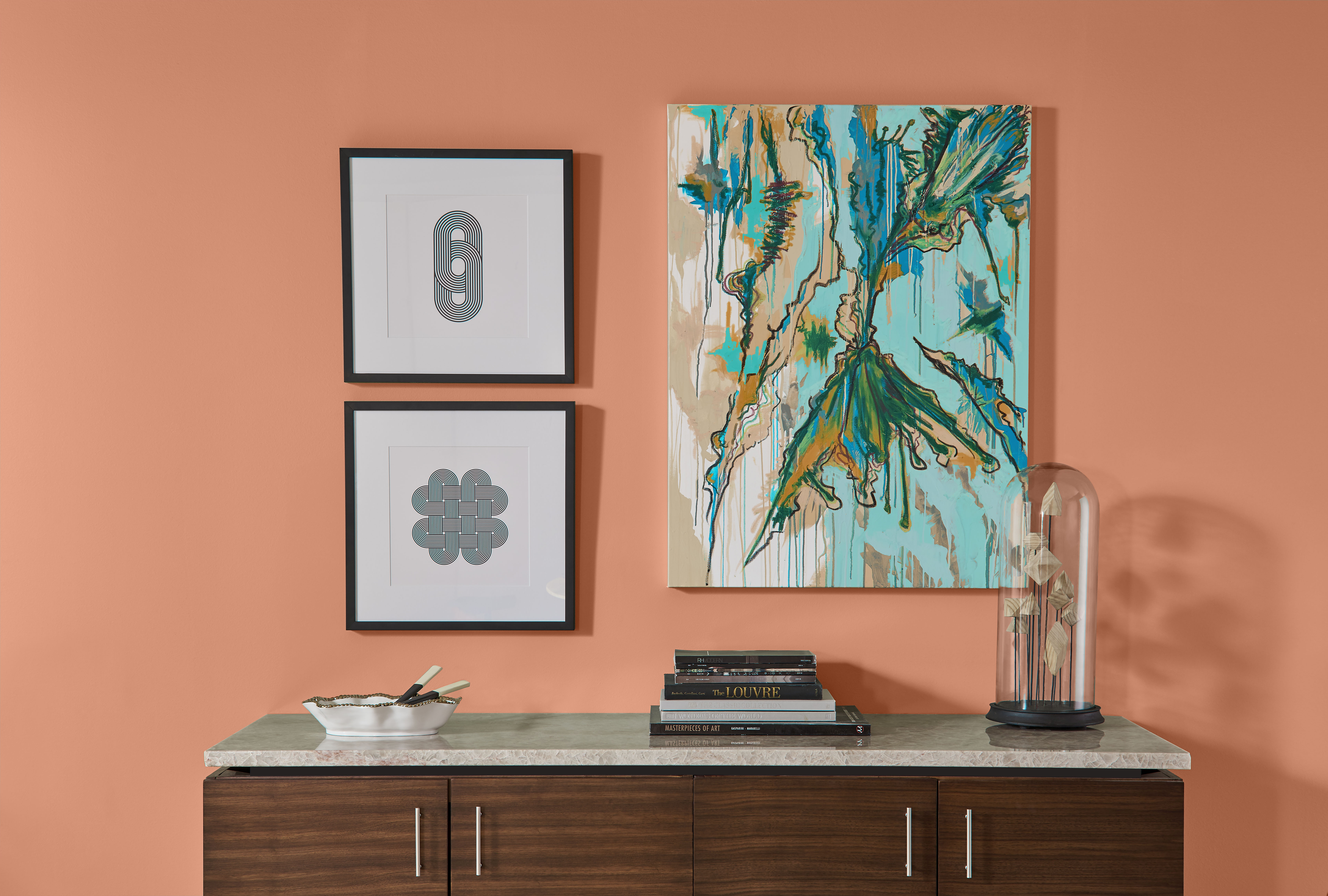 Console table styled against a warm clay-coloured wall with artwork above.