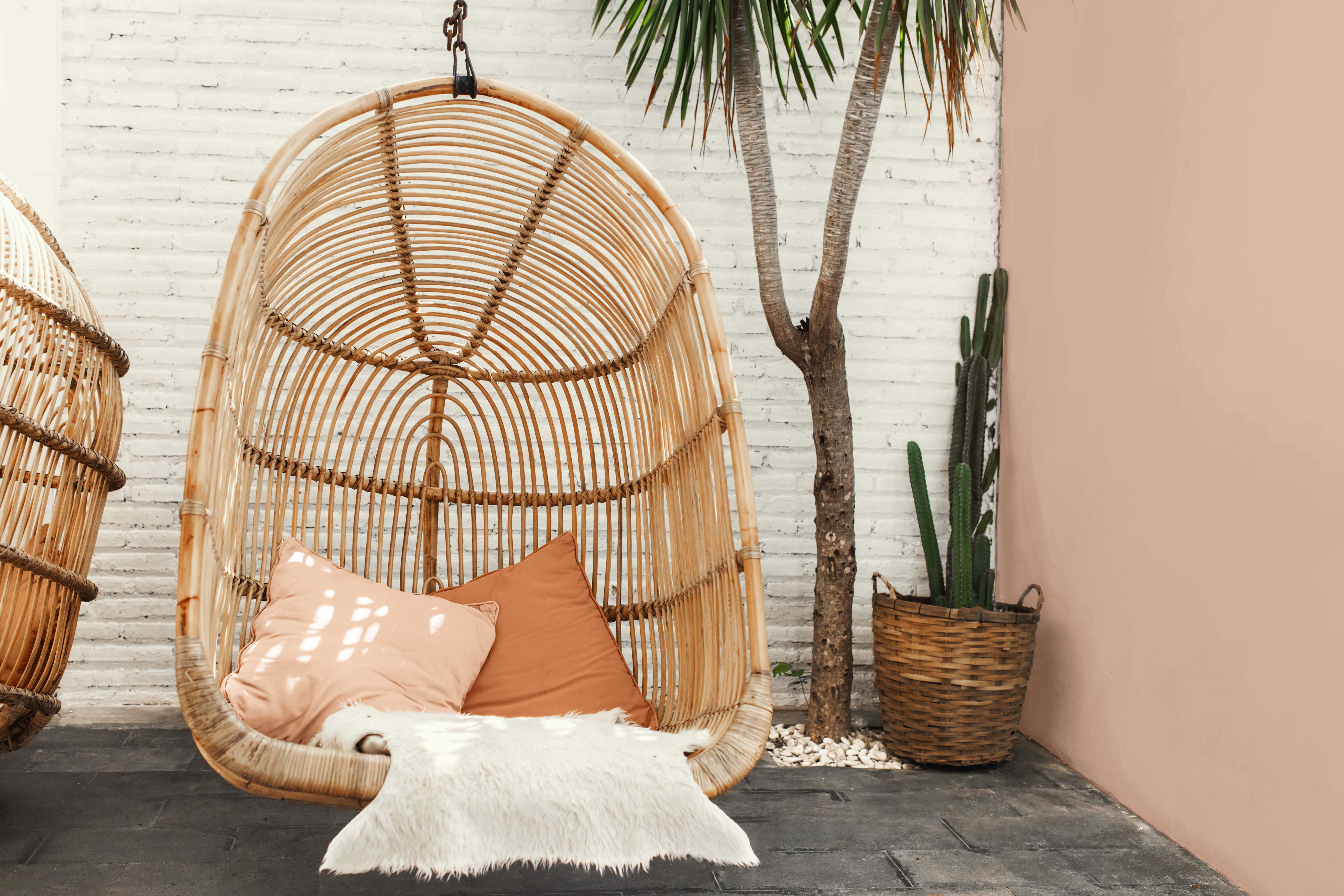 Alt text: A natural bamboo swing sits against a warm clay-toned wall.