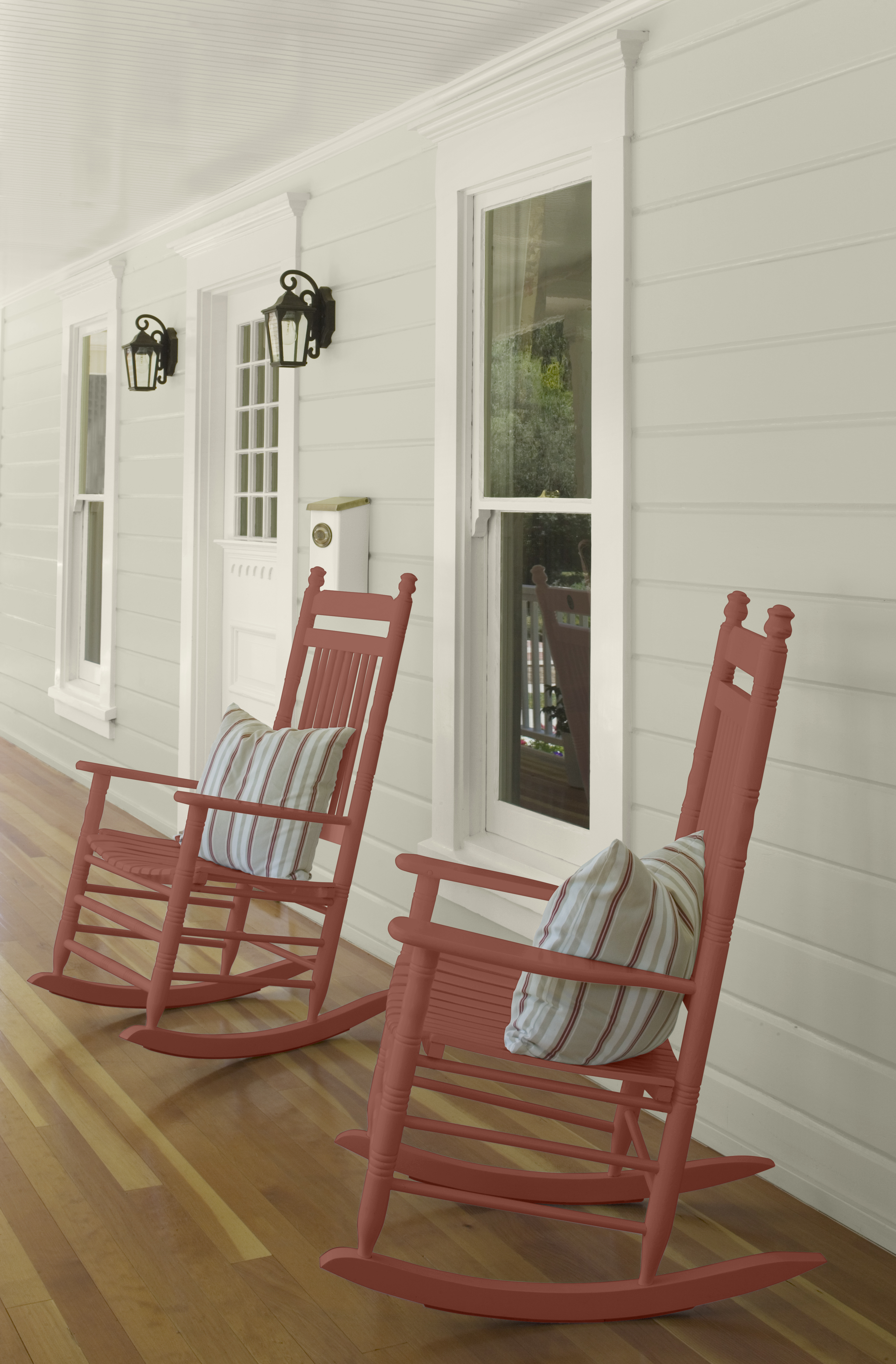 Alt text: Two warm-toned rocking chairs sit on a porch with soft green siding.