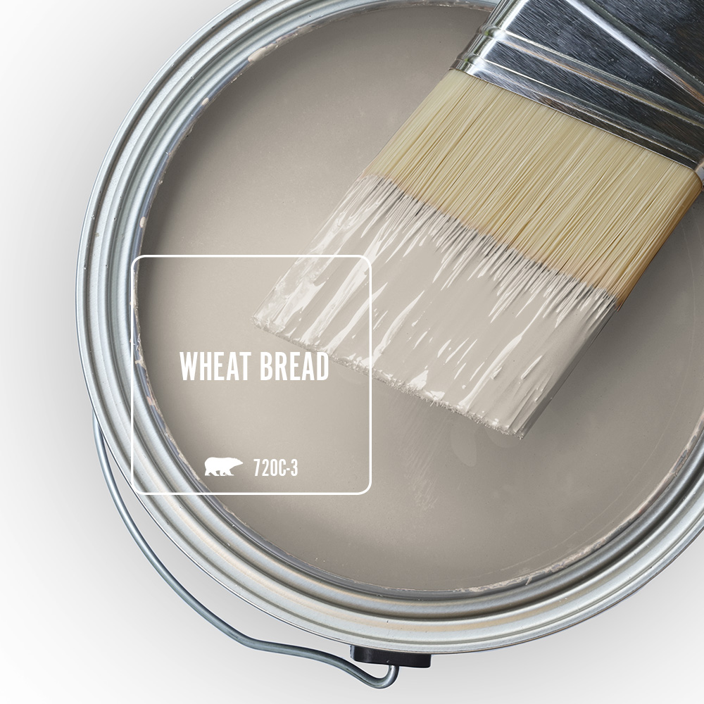 The top view of a paint can filled with Wheat Bread 720C-3, with a paintbrush resting across the soft taupe-grey paint colour.