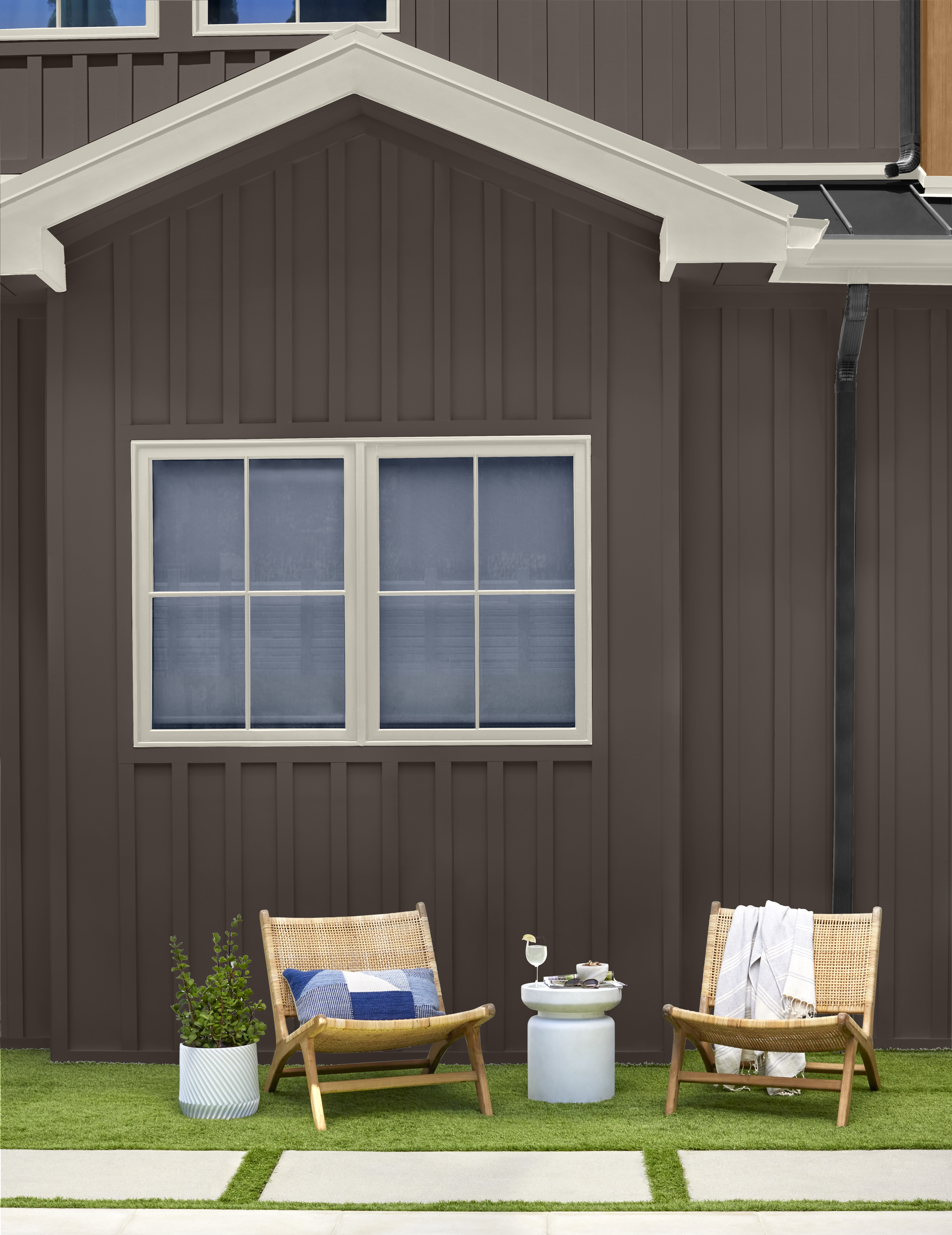 A cozy patio area featuring a deep, bold exterior colour that creates a warm and grounded backdrop for greenery and outdoor décor.