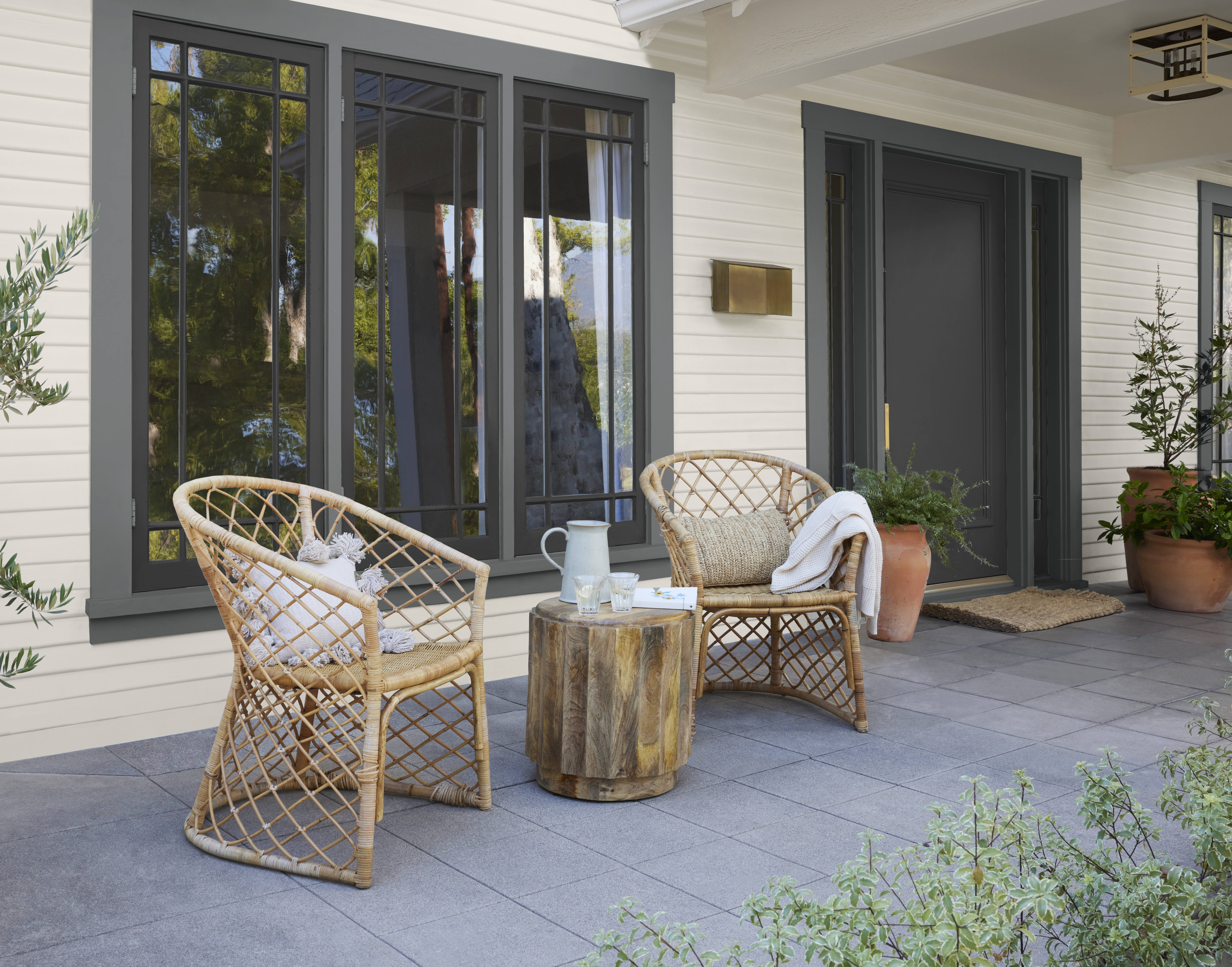 A small outdoor space with a light, warm-toned exterior and contrasting dark trim that highlights the home’s architectural details.