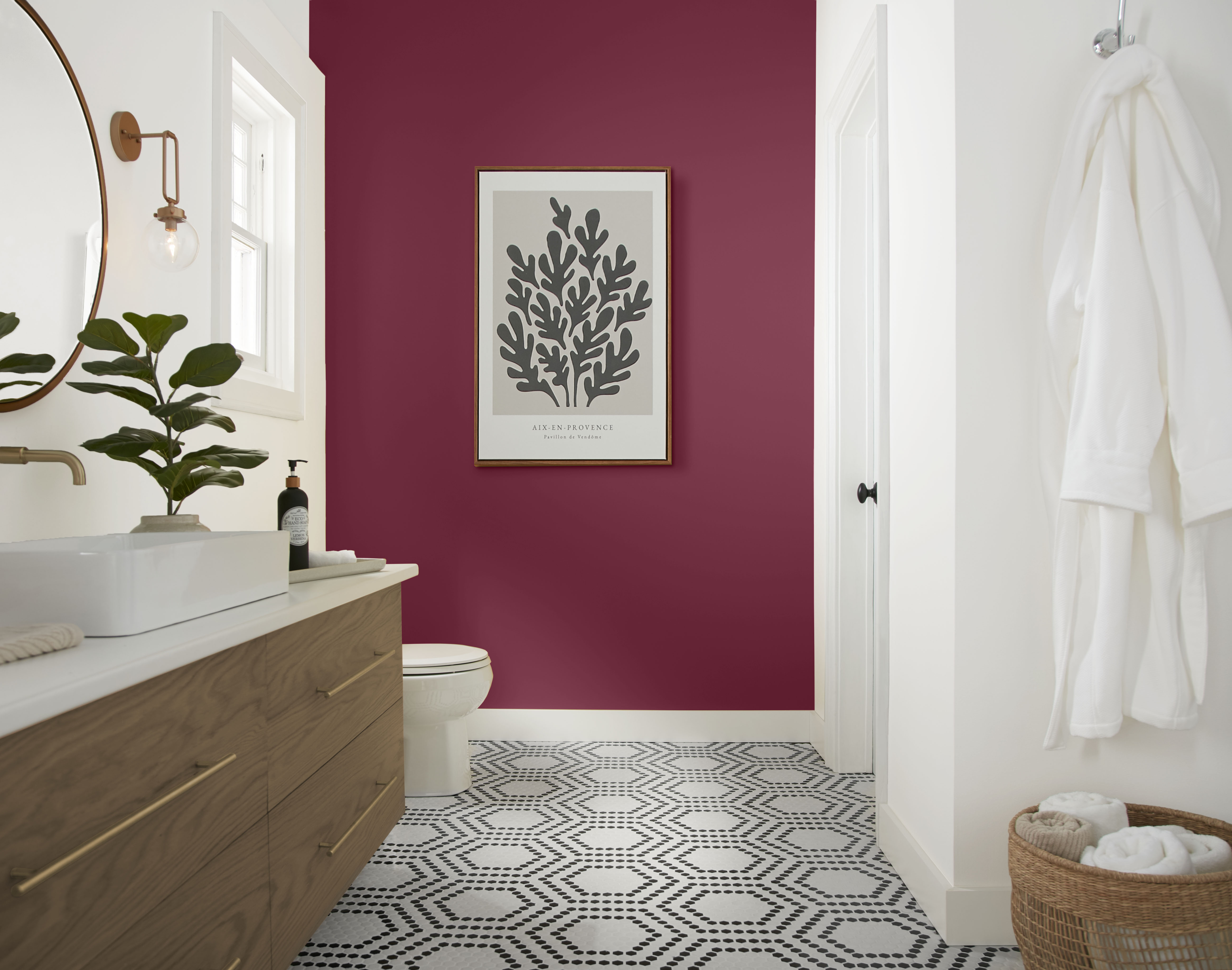Bathroom with Sugar Beet berry-toned accent wall, white trim, wood vanity, patterned floor tile, and soft spa-like styling.