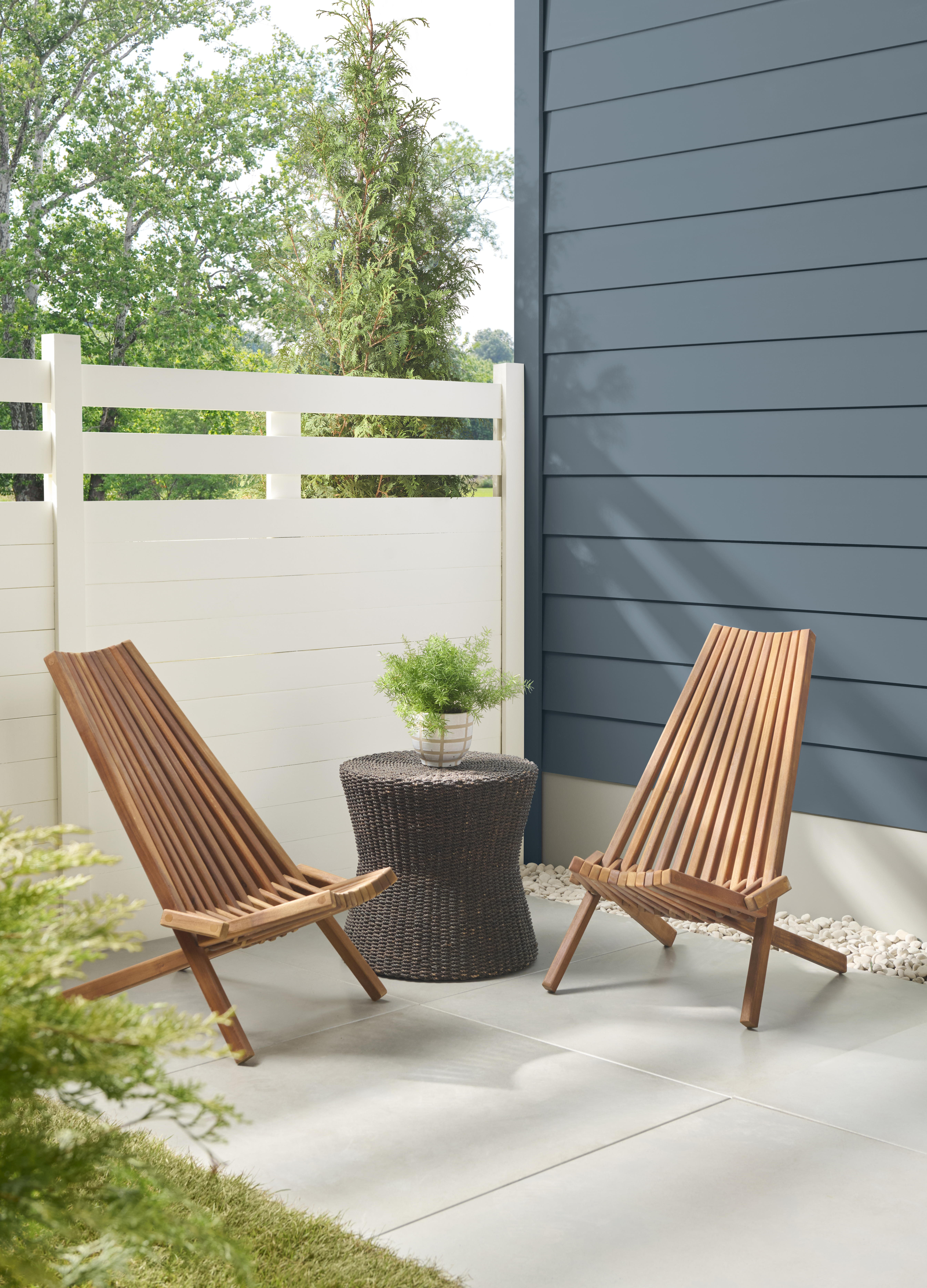 A charming backyard scene with a soft blue-toned home contrasted by a light, neutral fence for a fresh, open feel.