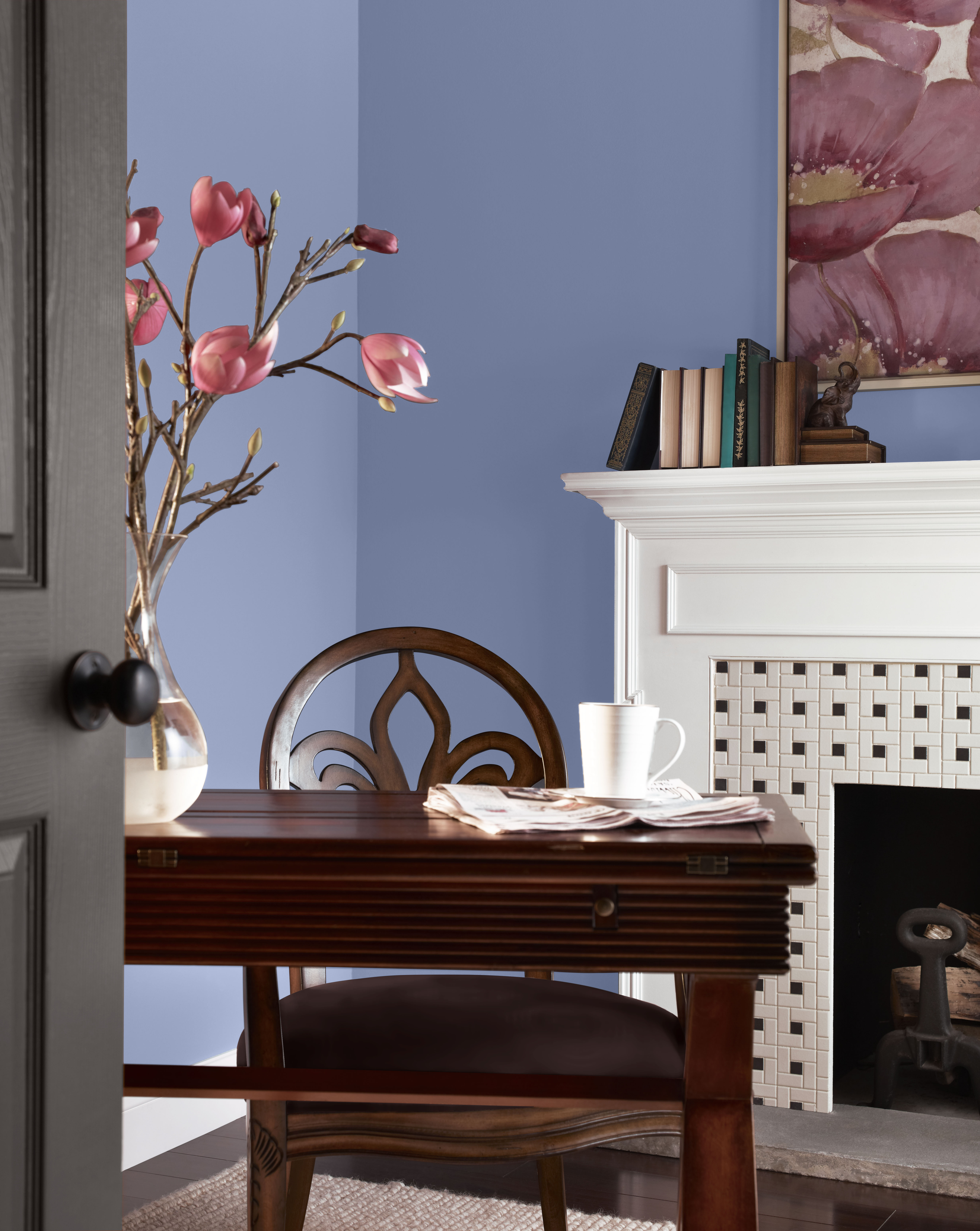 Office with Vintage Ribbon powdery blue-violet wall paint, white fireplace, warm wood desk, soft rose accents, and vintage-inspired details for a romantic Regency-style study.