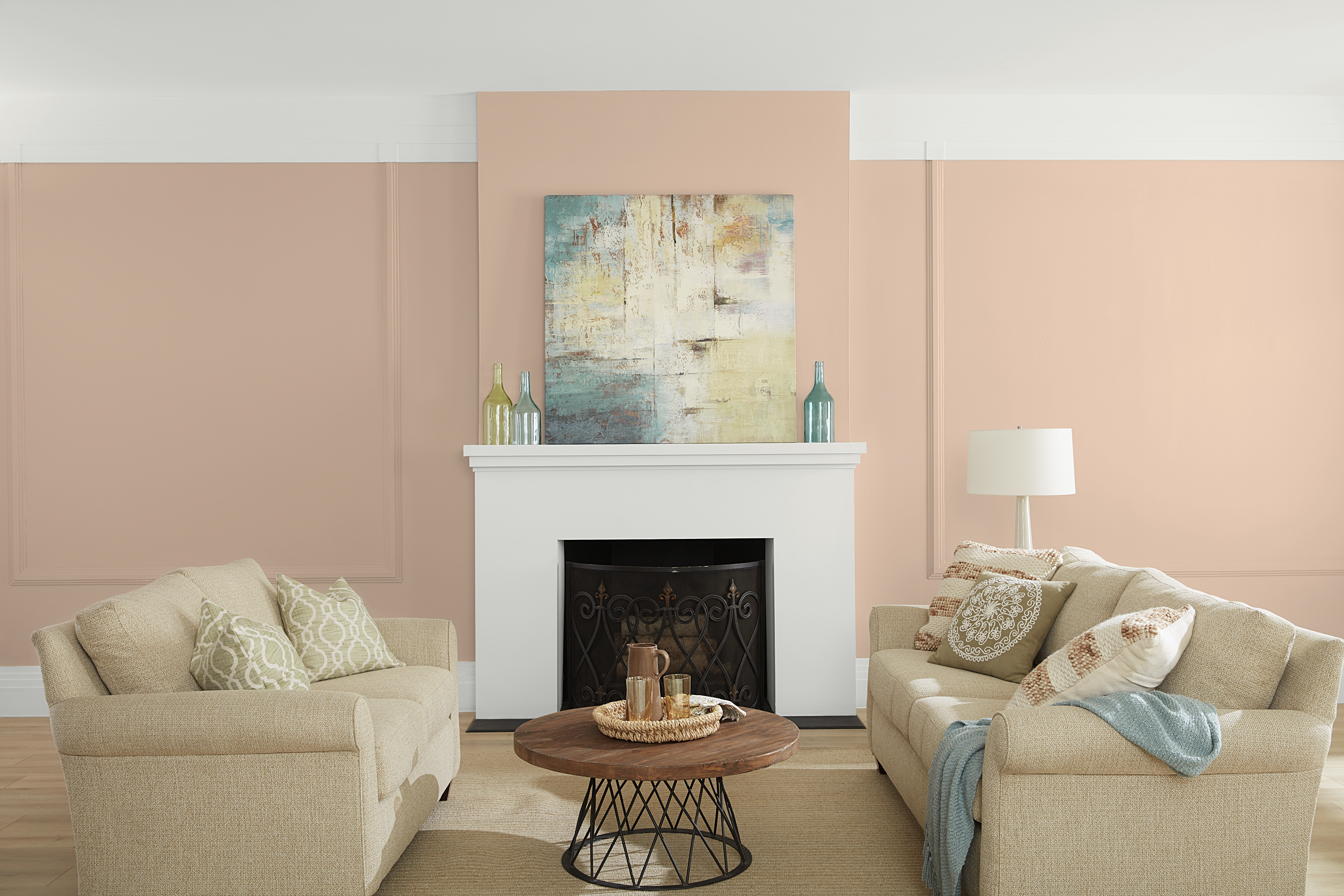 A living room featuring a subdued peach wall colour called Mesquite Powder with crisp white trim and fireplace, complemented by soft neutral seating, warm wood accents, and light blue decorative touches for an airy, inviting feel.