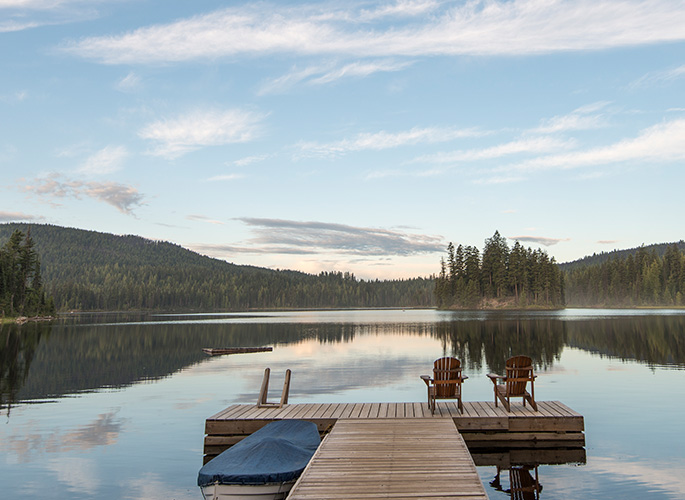 A wood dock that leads out to a quiet and calm lake.