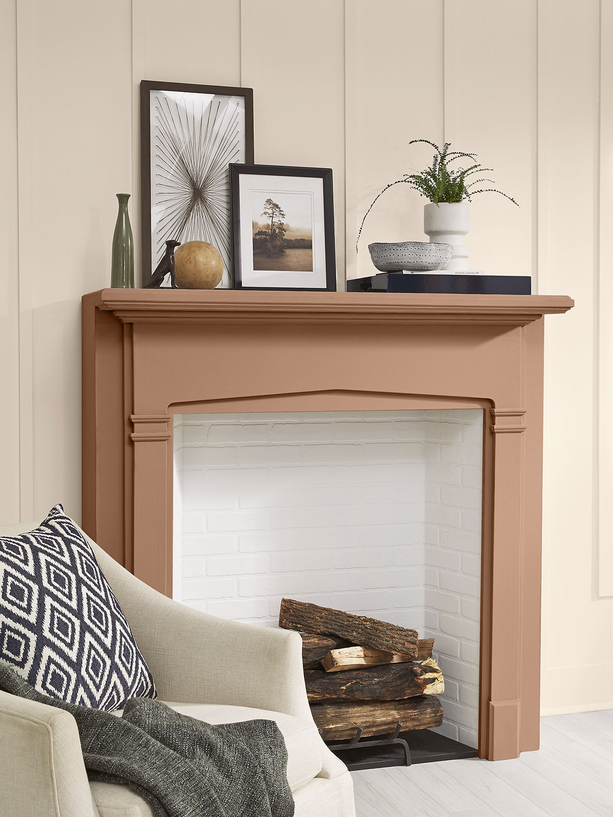 A tight crop of a living room with the focus on the fireplace that is painted in Canyon Dusk. The walls surrounding are white and there is a casual cream colored chair sitting on the side.