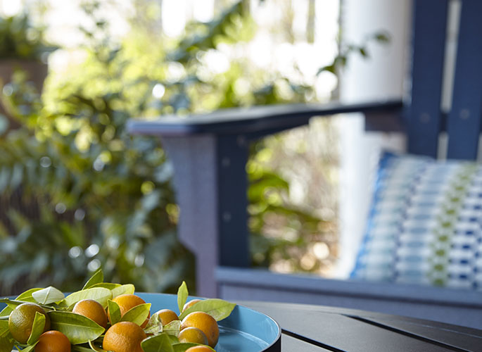 A very tight crop of a blue painted wood chair sitting outside on a front porch.