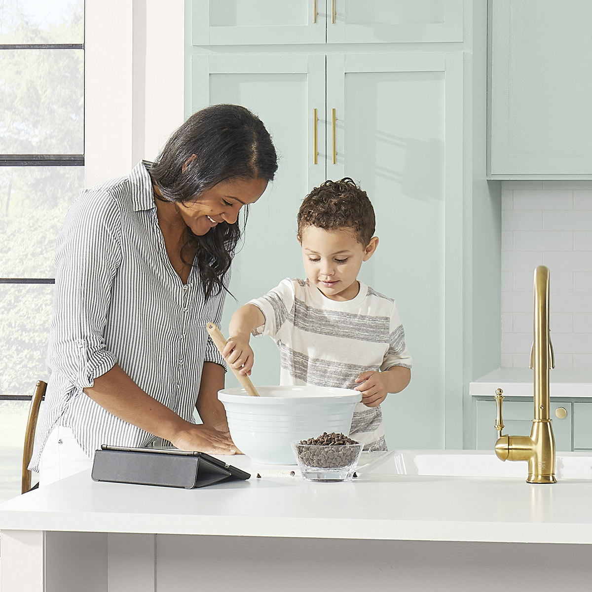 A mom and her son making cookies in the kitchen.